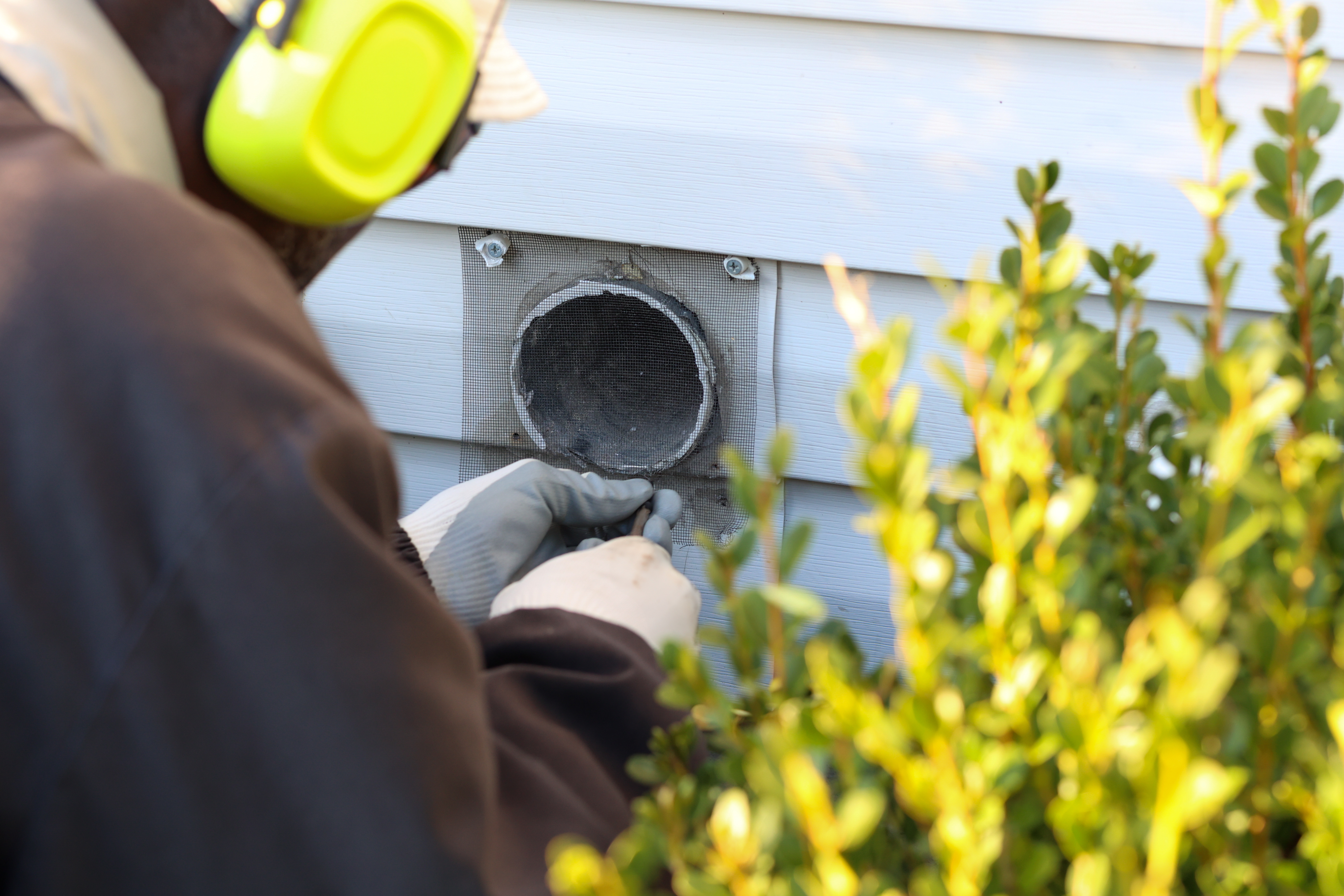 a portrait of a black man replacing a mesh covering over a dryer vent